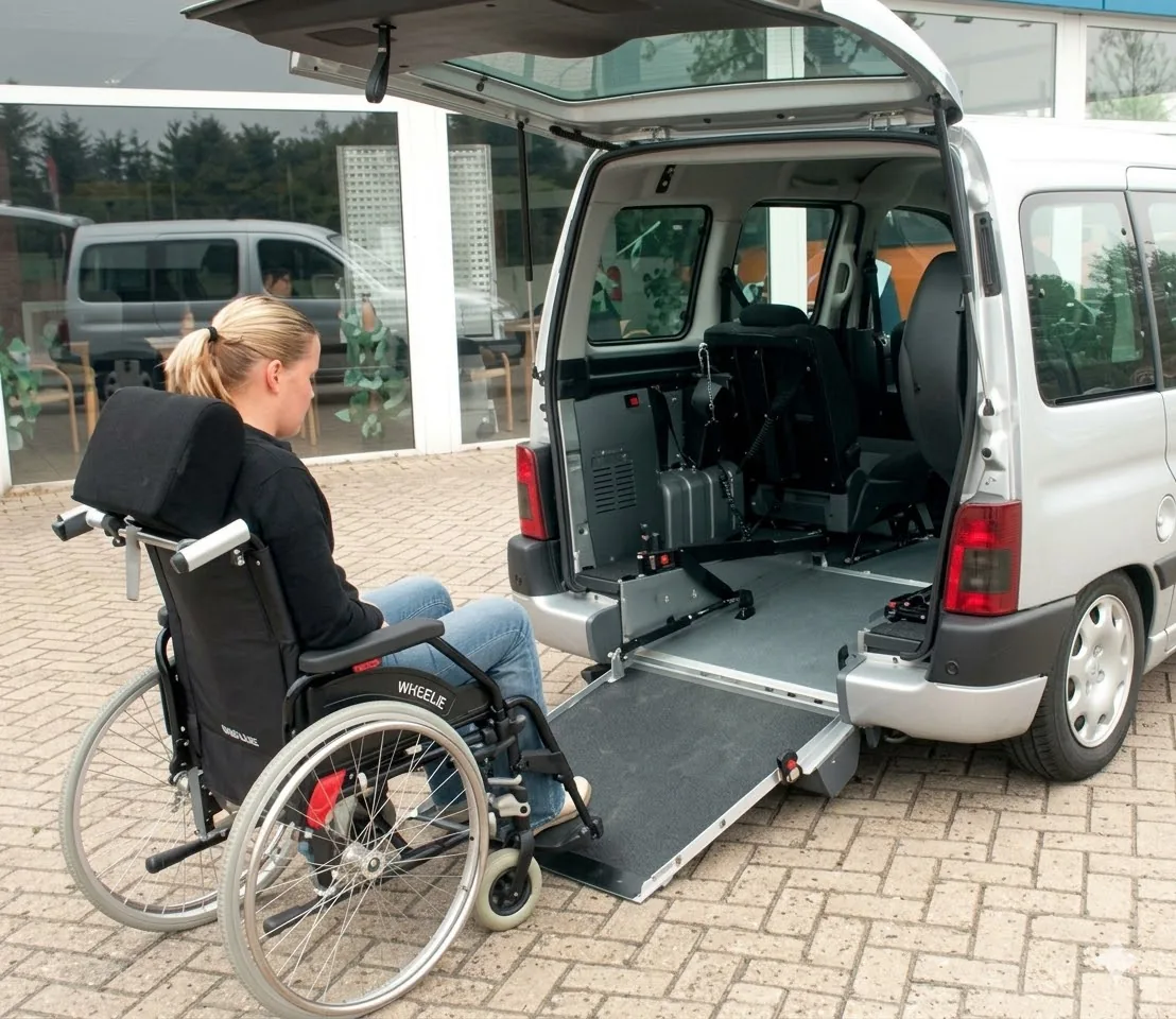 Rollstuhlfahrerin an der ausgeklappten Heckrampe eines umgebauten Hochdachkombis
